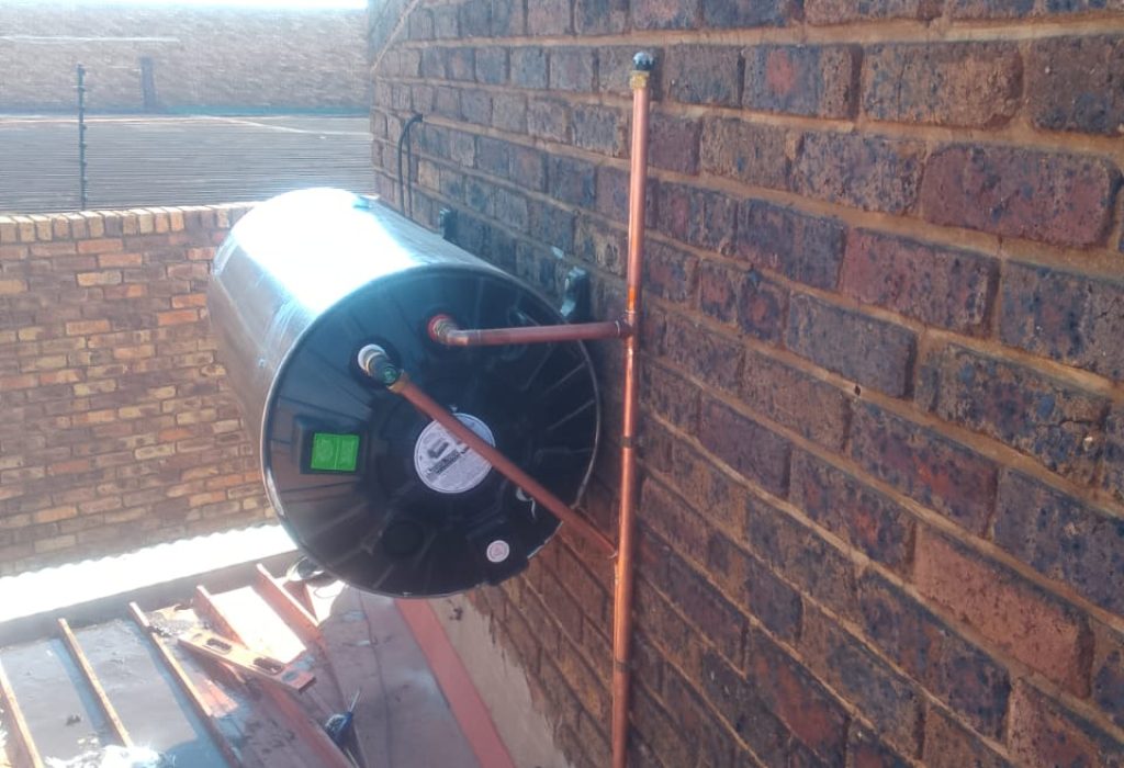 Technician installing a new geyser on a brick wall in Randburg