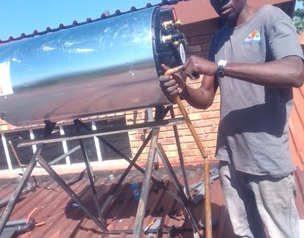 Technician installing a solar geyser on a roof in Randburg